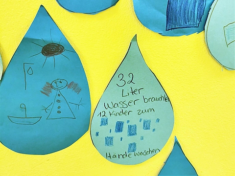 Basteleien in Regentropfenform hängen an der Wand der Kita.