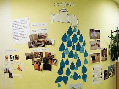Aushänge und Fotos zum Wasserprojekt hängen an der Wand im Kindergarten.