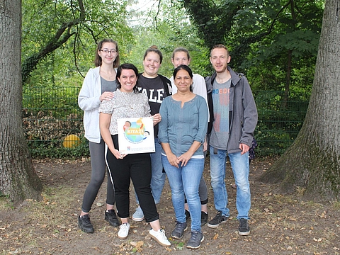 Fachkräfte aus dem Kindergarten An der Raa stehen zusammen und halten eine Urkunde.
