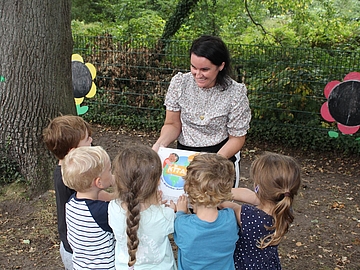 Die Kitaleiterin zeigt einer Gruppe Kindern die Urkunde zur Auszeichnung KITA21.